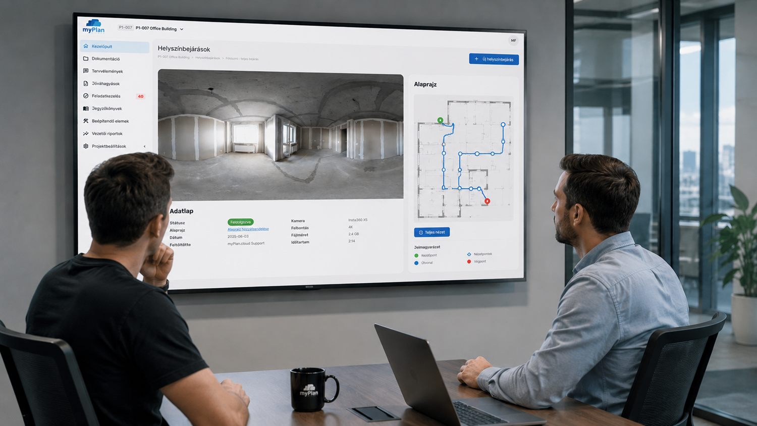 Project team reviewing a recorded 360° site walk and its floor plan on a large screen